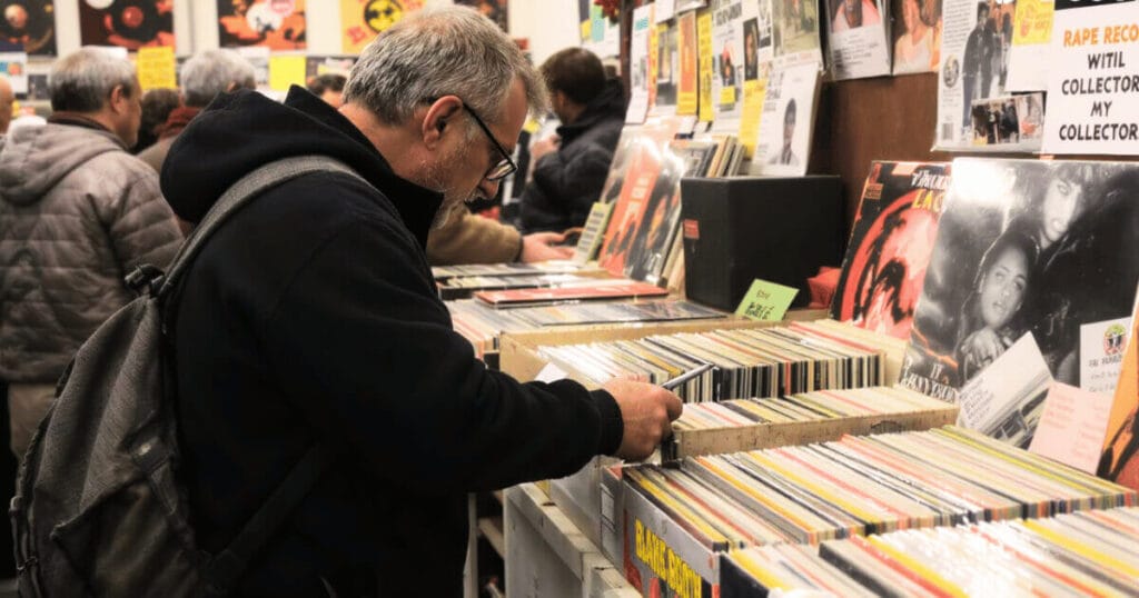 Colecionador de vinil procura vinis raros em uma loja de discos muito visitada.